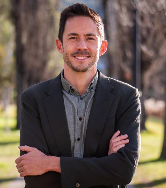 Dr Jason Chin standing outside, smiling with his arms crossed wearing a light grey shirt and dark grey blazer.