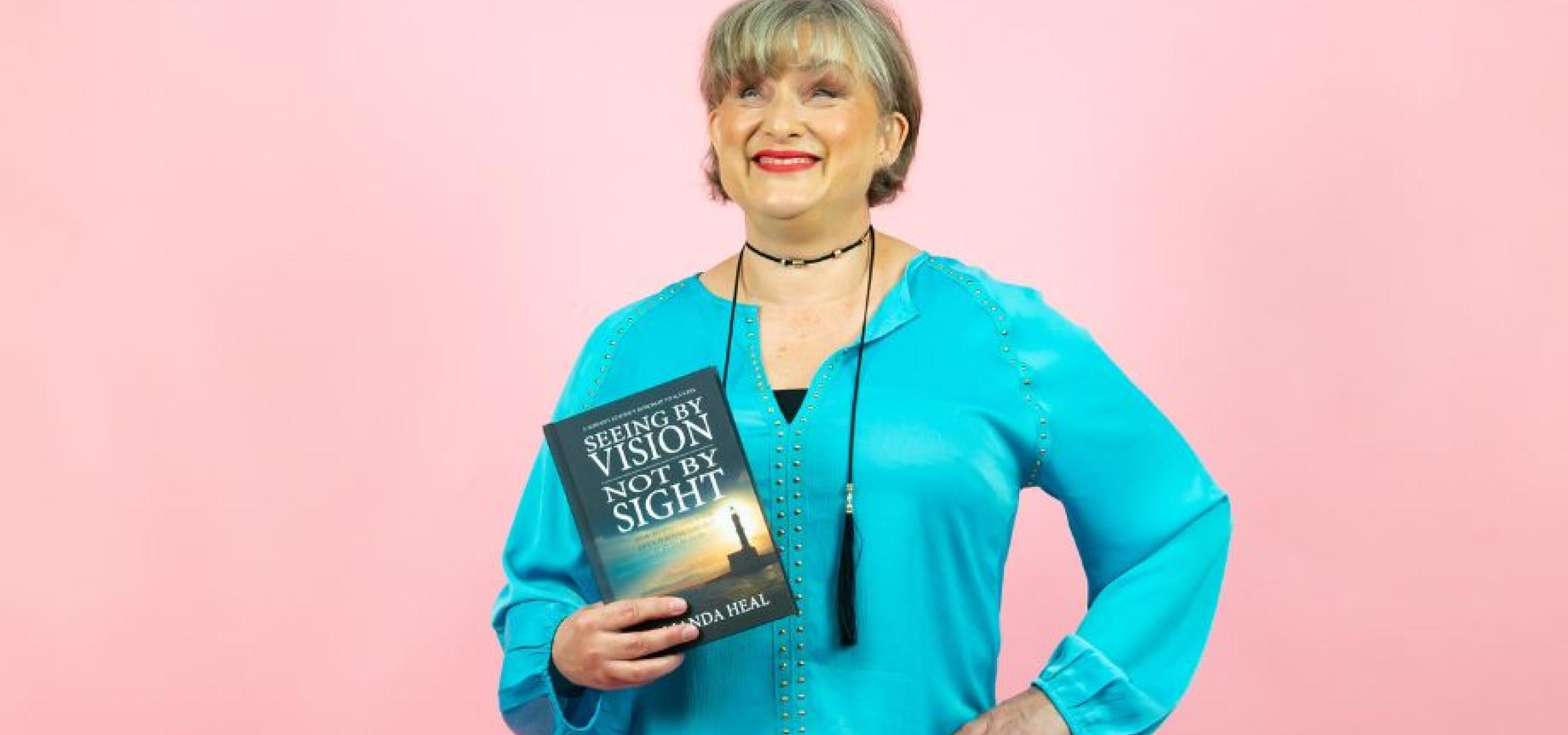 Amanda Heal poses with her book, 'Seeing by Vision Not by Sight'